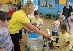 Przedszkolaki segregują śmieci do odpowiednich worków.